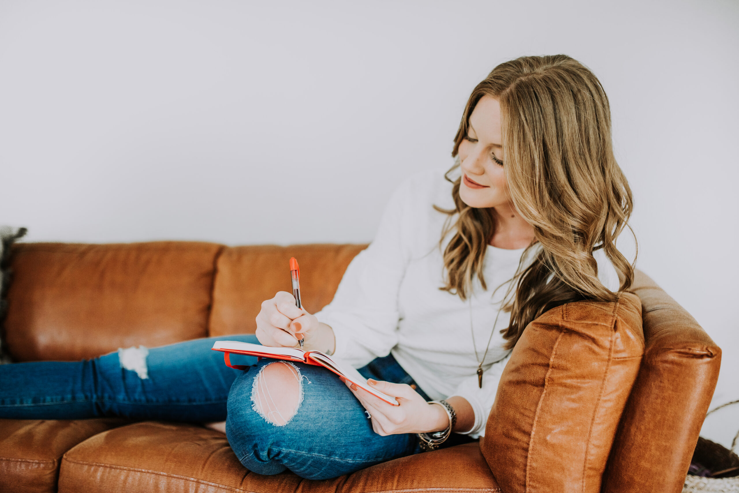Alyssa writing in notebook on couch